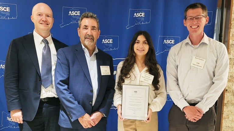 Four individuals posing in front of an ACEC banner, each wearing business attire and name tags.