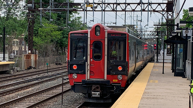 Red train on railroad tracks at a train station platform.