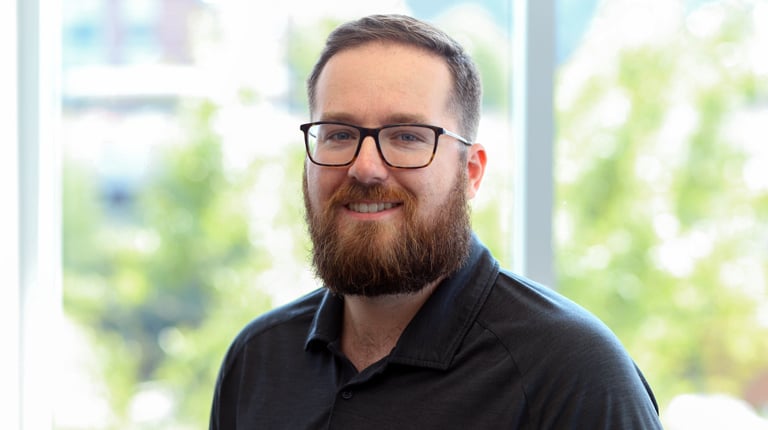 Dan Gleason smiles at the camera wearing a black polo shirt.  