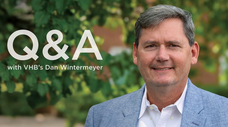 Head shot of Dan Wintermeyer in a light blue suit with a white shirt outdoors with trees in the background.