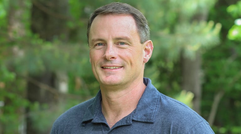 Doug DeBerry smiling at the camera in a blue polo shirt.