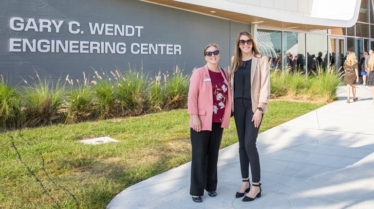 Ivy Clinton and Cameron Langerman stand in front of the new building.