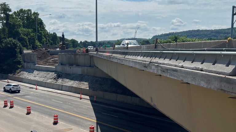 View of a highway under construction with traffic cones lining the lane barriers, under a clear sky.
