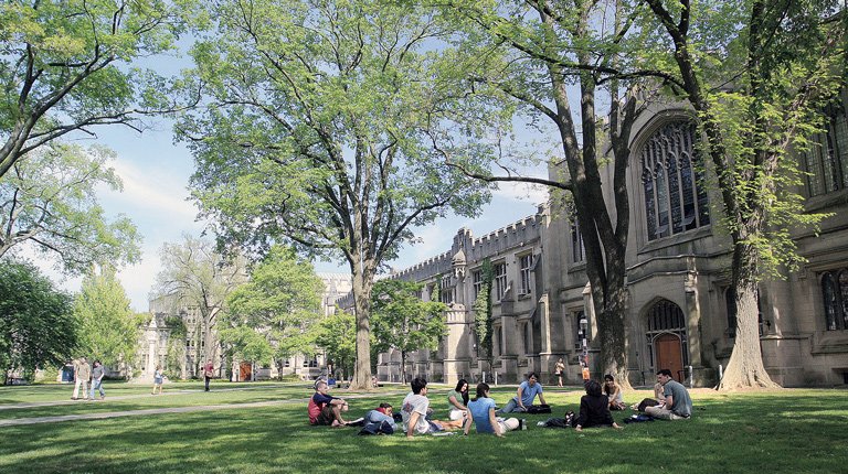 Students sit in the grassy shade on Princeton University’s campus 