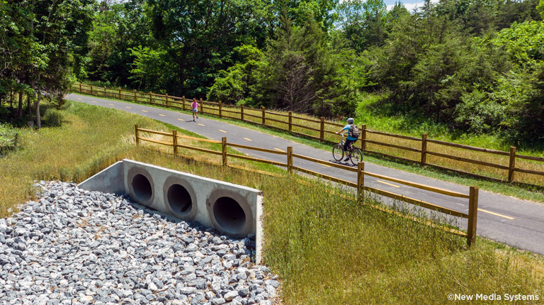 One bike rider and one runner use a section of the trail built across a culvert.