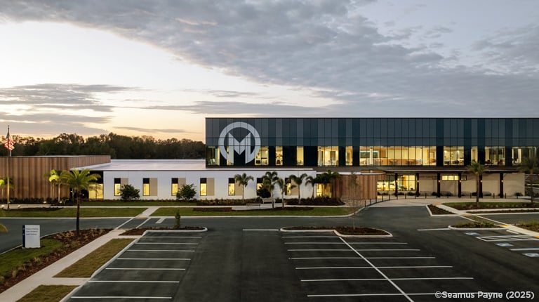 A healthcare building with an M on its exterior facade at sunset.