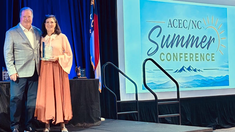 Jenny Fleming stands on stage holding her award with Michael Holder, former ACEC/NC President.  