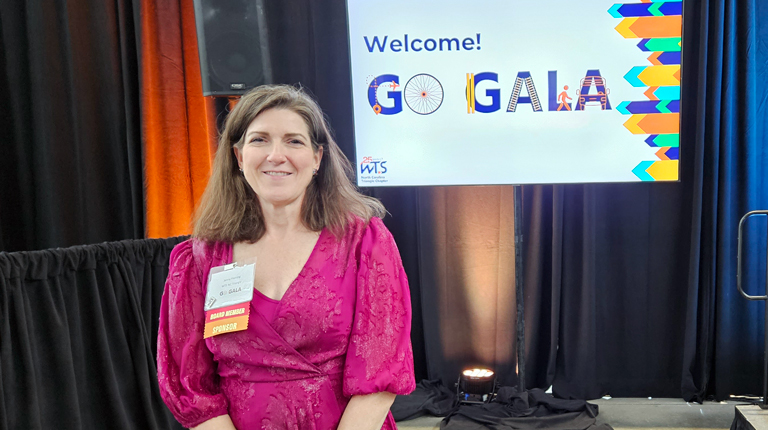Jenny Fleming smiles at the camera in front of Go Gala sign. 
