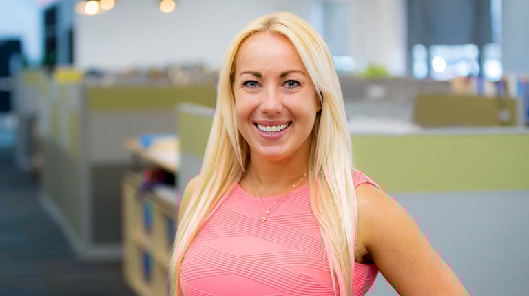 Kathleen wears a pink blouse in an office setting.
