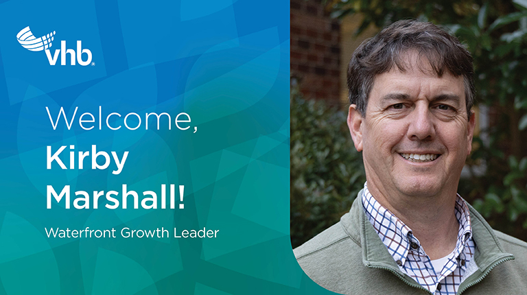 Kirby Marshall smiling in front of magnolia trees and a tan quarter zip.