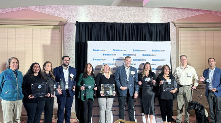 Award winners holding their awards in front of backdrop.