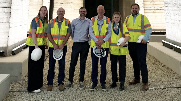 Group of six VHBers standing in the undercroft next to the illuminated concrete foundations.