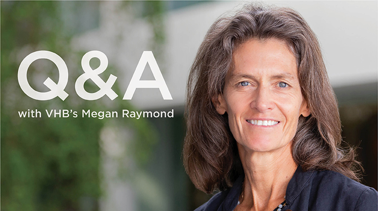 Megan Raymond in an office setting wearing a navy-blue top. 