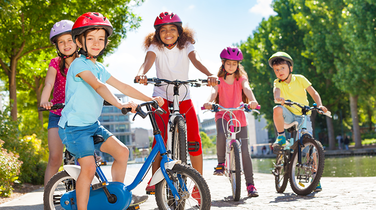 Children ride bikes in city park