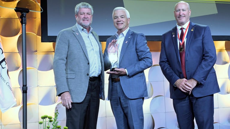 Three men smiling on stage.