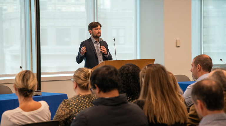 Ryan Prime speaking at an event in front of crowd. 