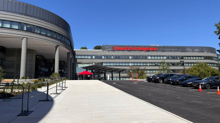 A hospital building with cars parked in front of it.