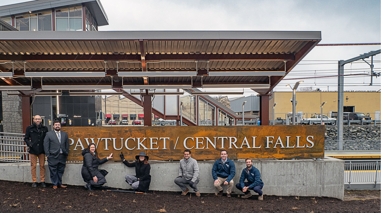 Group of people in front of a metal sign.