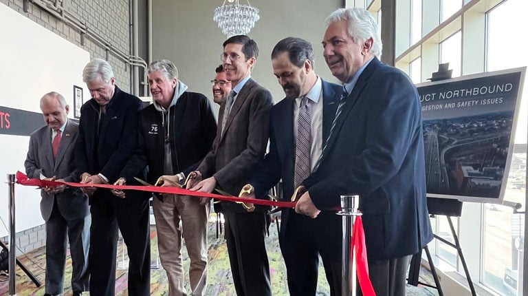 A group of men cutting a red ribbon.
