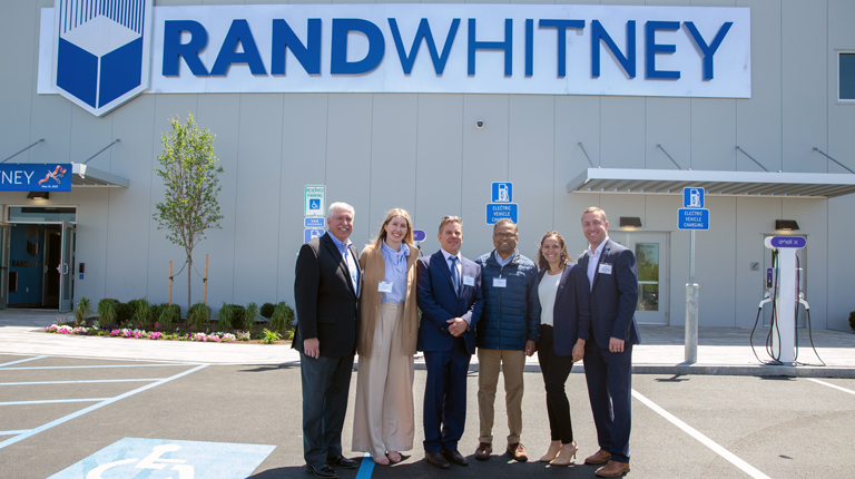 Ted Fire, Annie Gorman, Nick Smith, Vinod Kalikiri, Brittany Gesner, and Kyle Merkosky stand in front of an industrial facility.