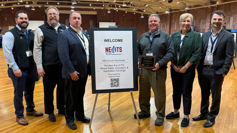 Six people around an NEITS welcome sign, with Ron Hartman holding his ITS award.