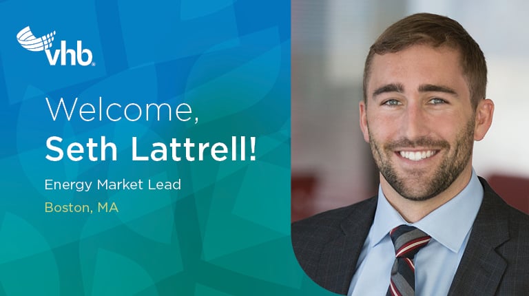 Seth Lattrell posing in the office with a suit and tie.