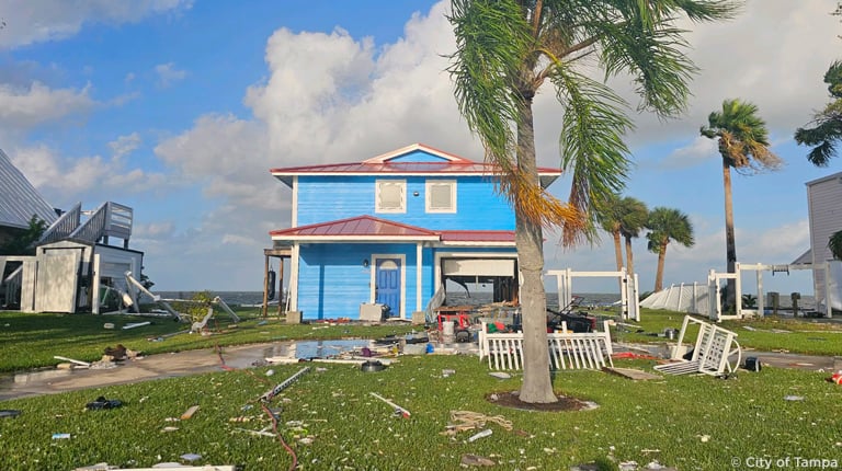 A blue beach house with storm damage on the coast.