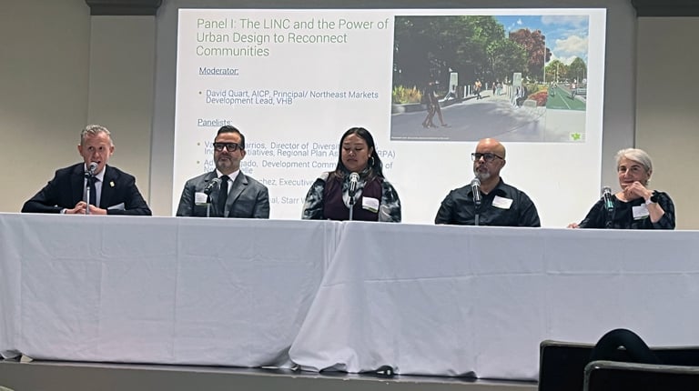 David Quart sitting at a table with panelists in front of the LINC presentation. 