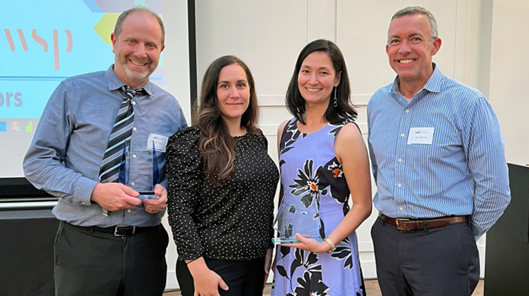 Two women and two men standing together with two awards.