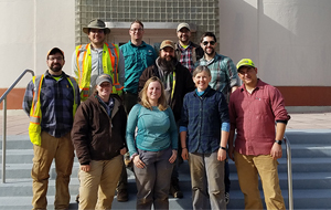 A team of archaeologists stand on the steps of a National Park Service building