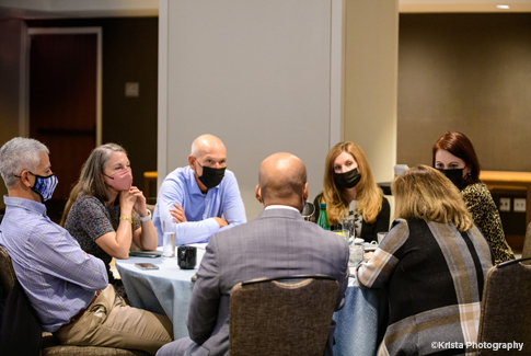 A group of men and women in discussion around a table.