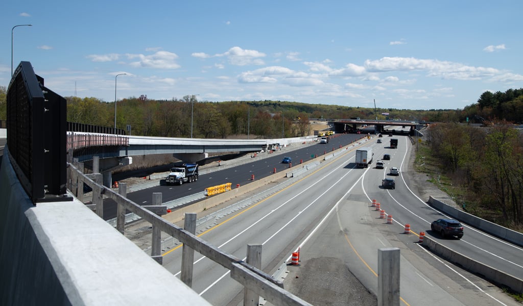 A highway scene showing a multi-lane road with several vehicles, including a visible truck. An overpass crosses above the highway.