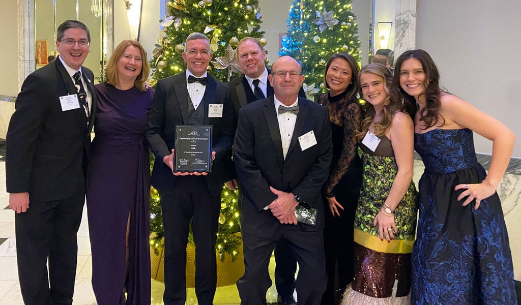Group of VHB staff with award in front of Christmas tree at the 2025 ACEC/MW Engineering Excellence Awards Gala on December 16