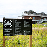 Arverne East Nature Preserve sign with building in background. 