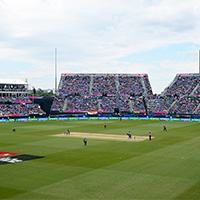 Cricket stadium with players on the field. 