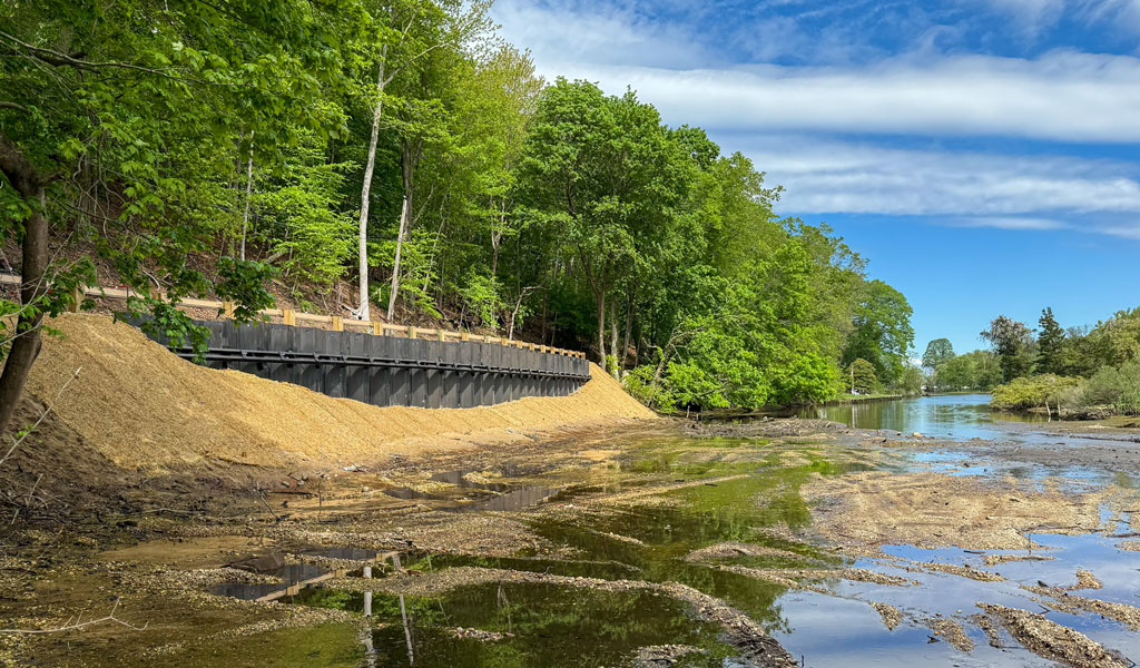 Stabilized embankment along Mill Creek Road protecting roadway and restoring creek corridor after flooding.