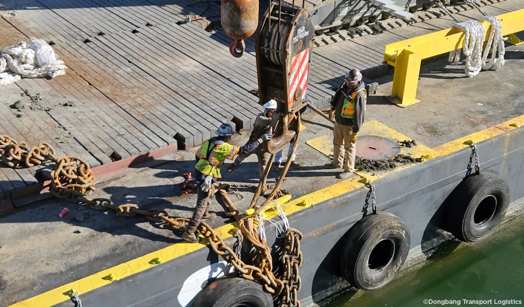 Three men in protective gear overseeing the recovery of a lost anchor out of the channel.