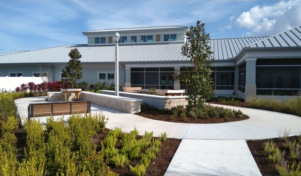 A garden, bench and path in front of a one story Veterans nursing home 