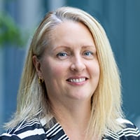 Regan Hammond smiles at the camera in a striped blazer.
