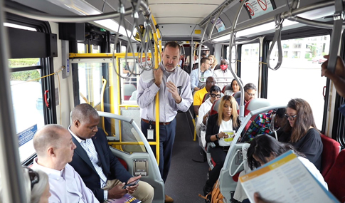 San Diego trip delegates are standing and seated on a commuter bus