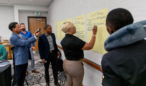 San Diego trip delegates are brainstorming ideas on a large piece of paper during a workshop.