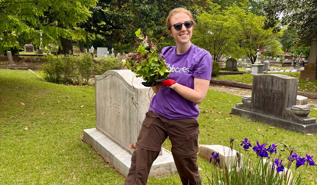 A woman in a purple shirt working in a landscape.