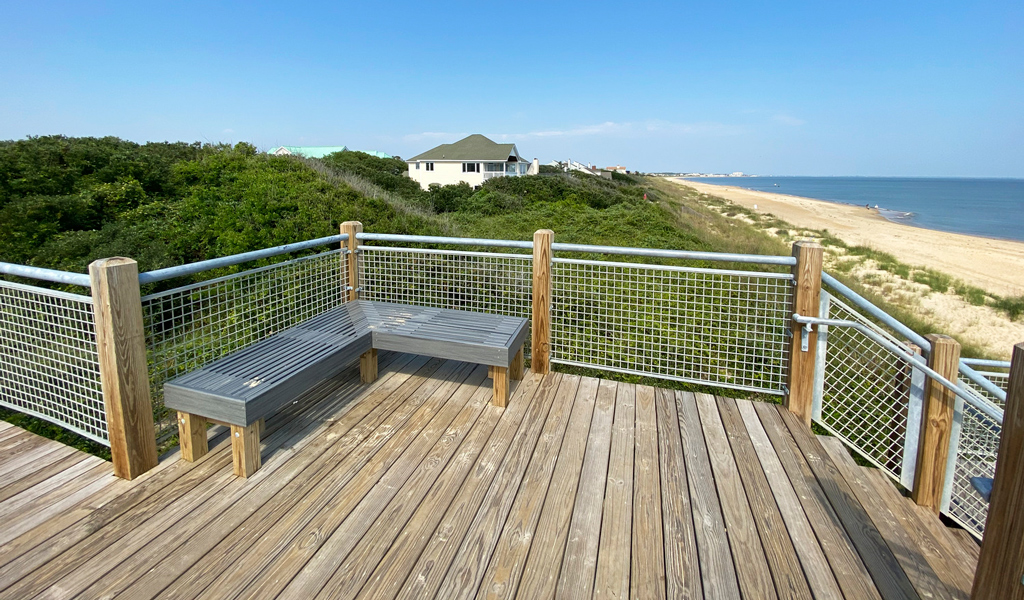 A bench at the top of the boardwalk with views of the dunes and Chesapeake Bay.