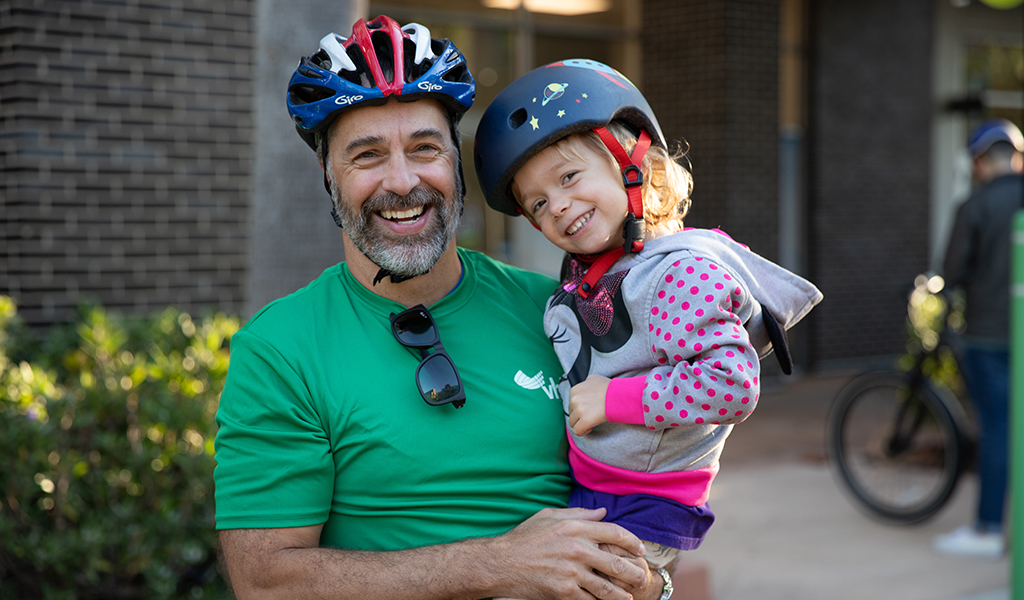 Marc Hustad holds a child wearing bicycle helmets