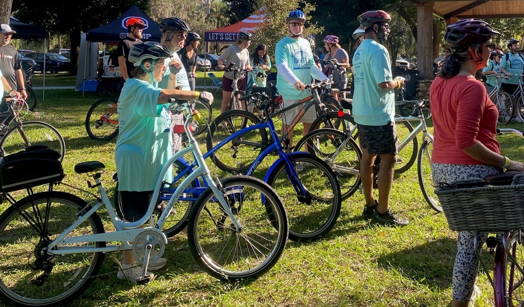 Group of cyclists chatting on grass ahead of the group ride.