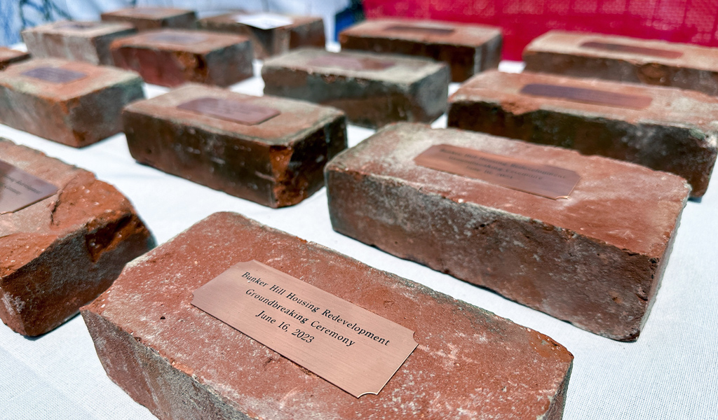 Red bricks with plaques on them that celebrate a groundbreaking.