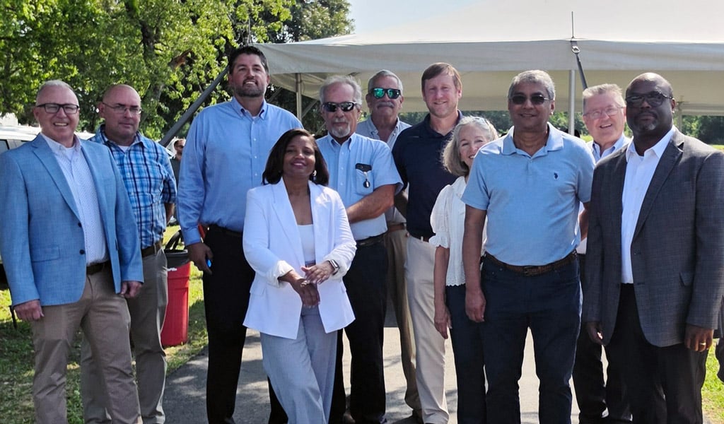 A group of adults smiling at a bike path opening.