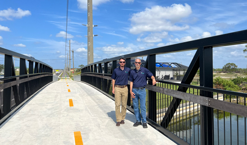 Marc Bertoncini and Kenneth Ray stand on a multimodal trail bridge over a canal