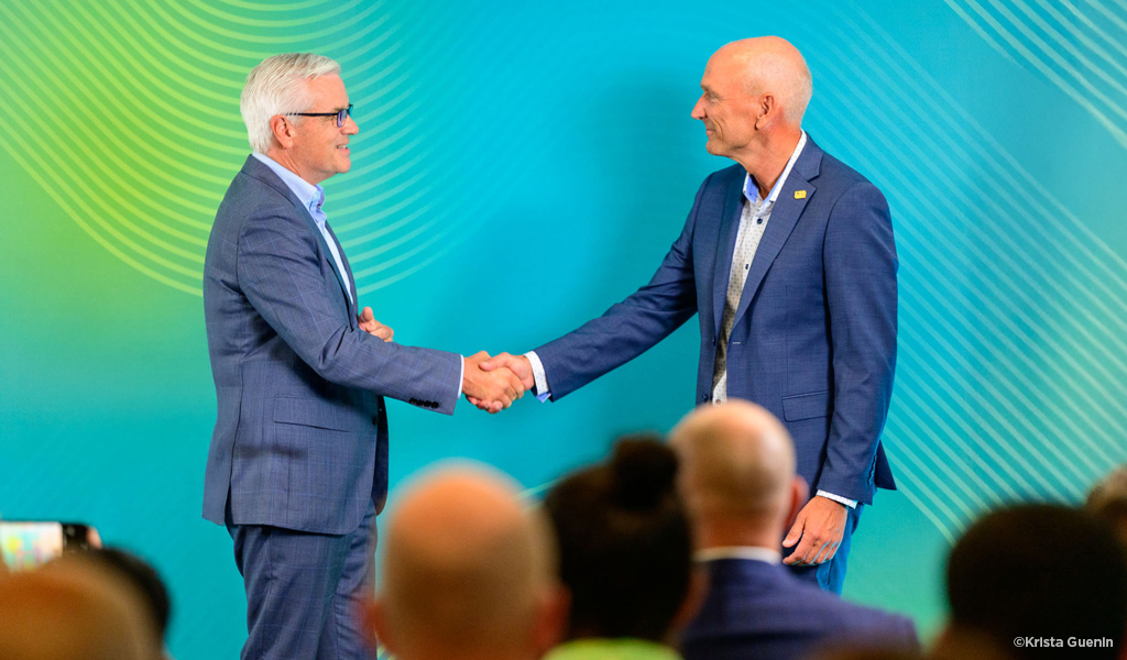 Mike Carragher & Bill Ashworth on stage in front of a colorful backdrop.