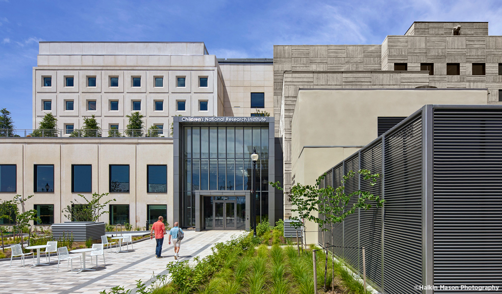 Two people walking up to the front entrance of the Children’s National Research and Innovation Campus.